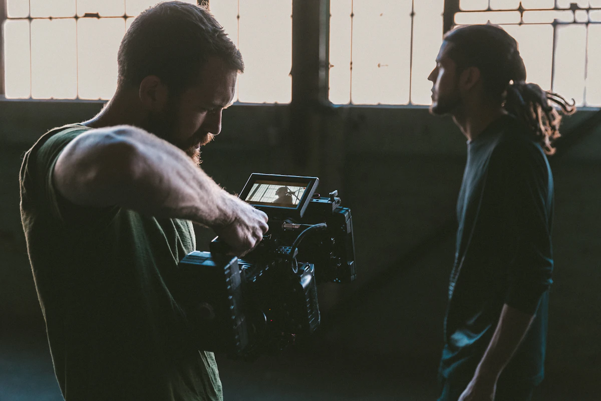 A camera operator filming another person against a wall