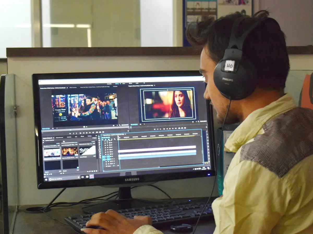 An editor in headphones working at a computer