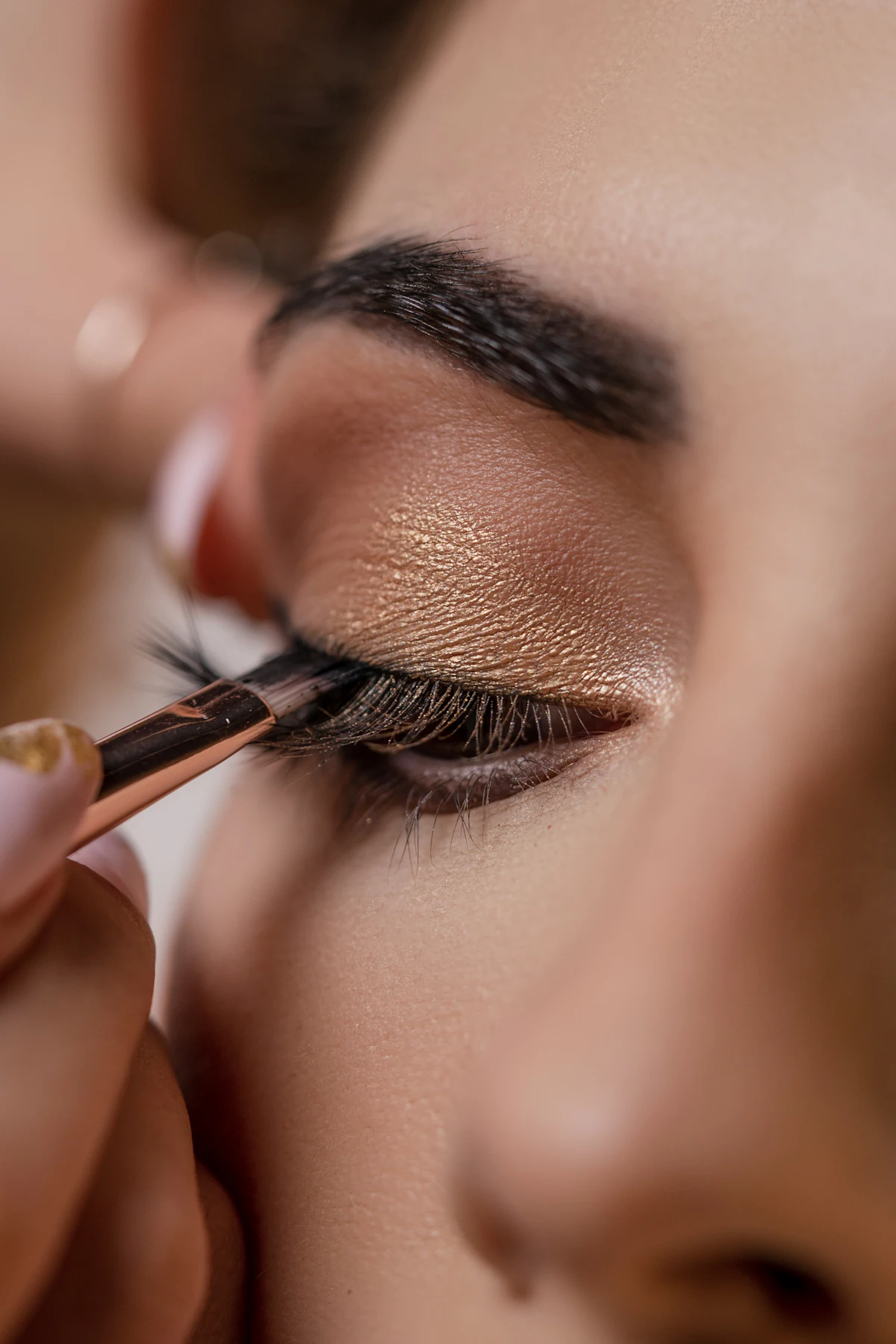 A makeup artist applying gold eyeshadow with a fine brush