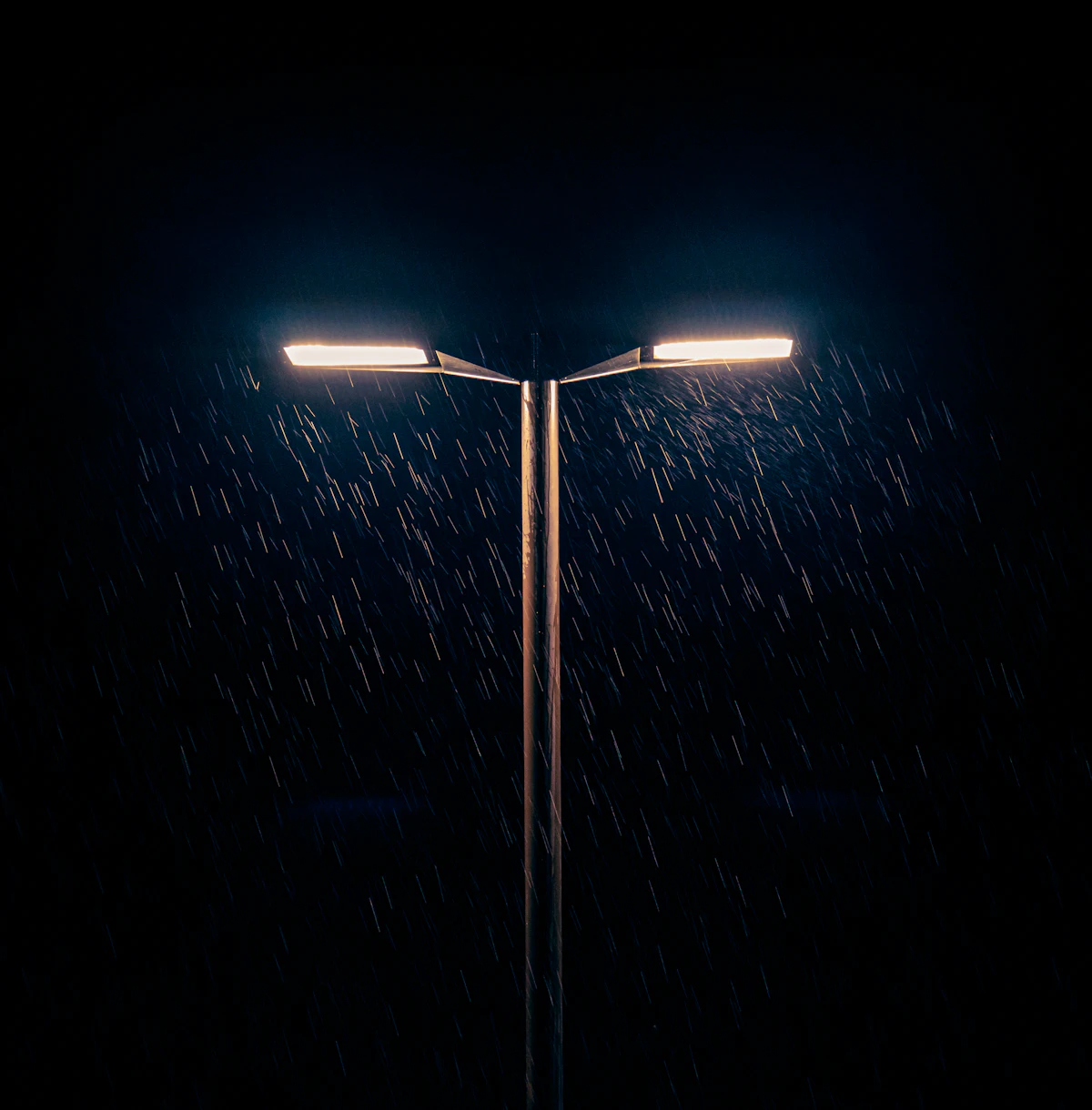 A street light glowing in the rain at night