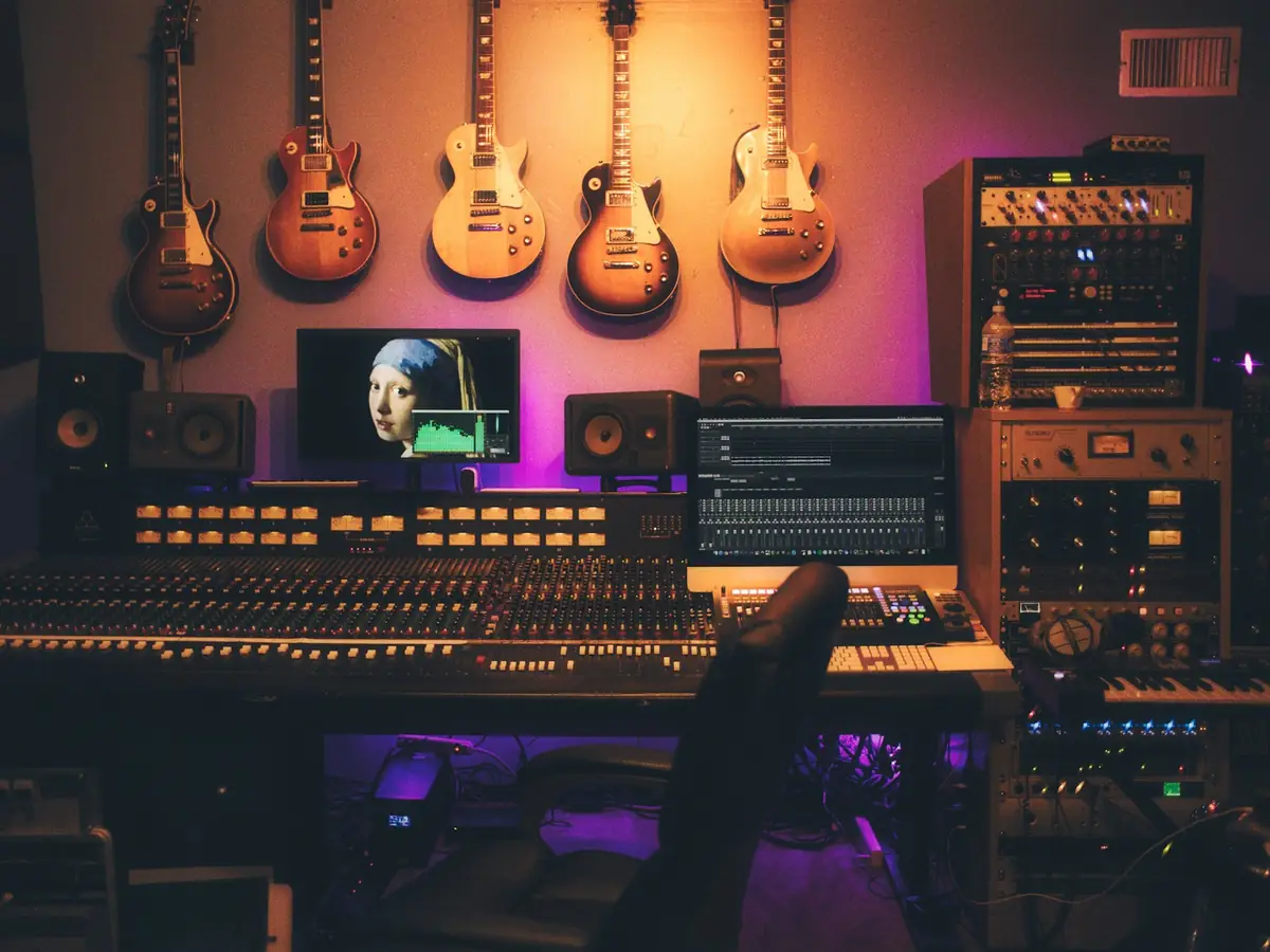 A recording studio with a mixing desk and guitars on the wall