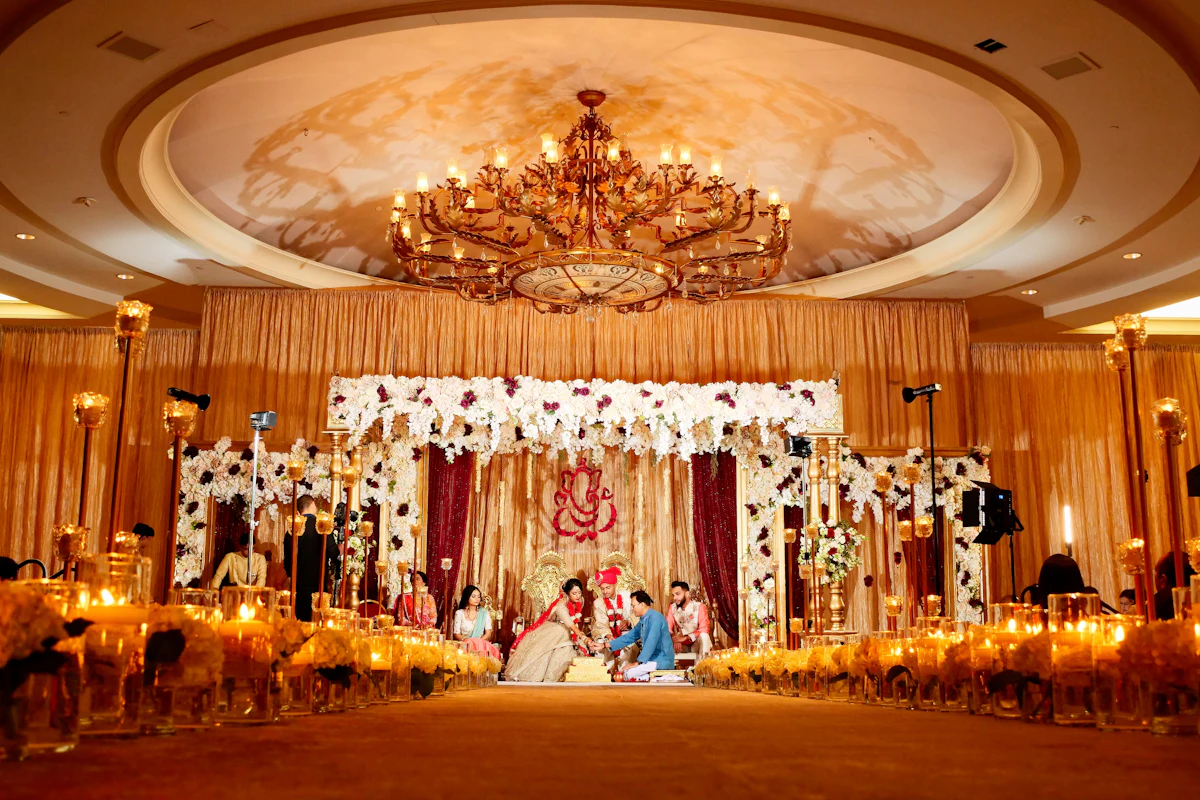 A couple performing a wedding ritual under a floral mandap